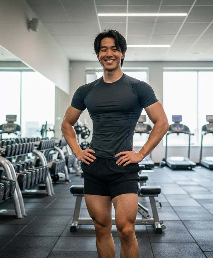Man posing in a gym wearing a dark athletic outfit
