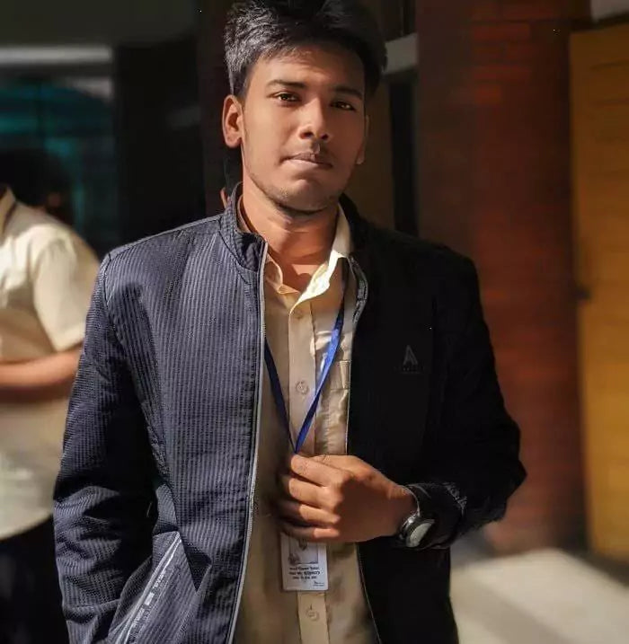 Man wearing a dark jacket over a light shirt with a lanyard, standing outdoors.